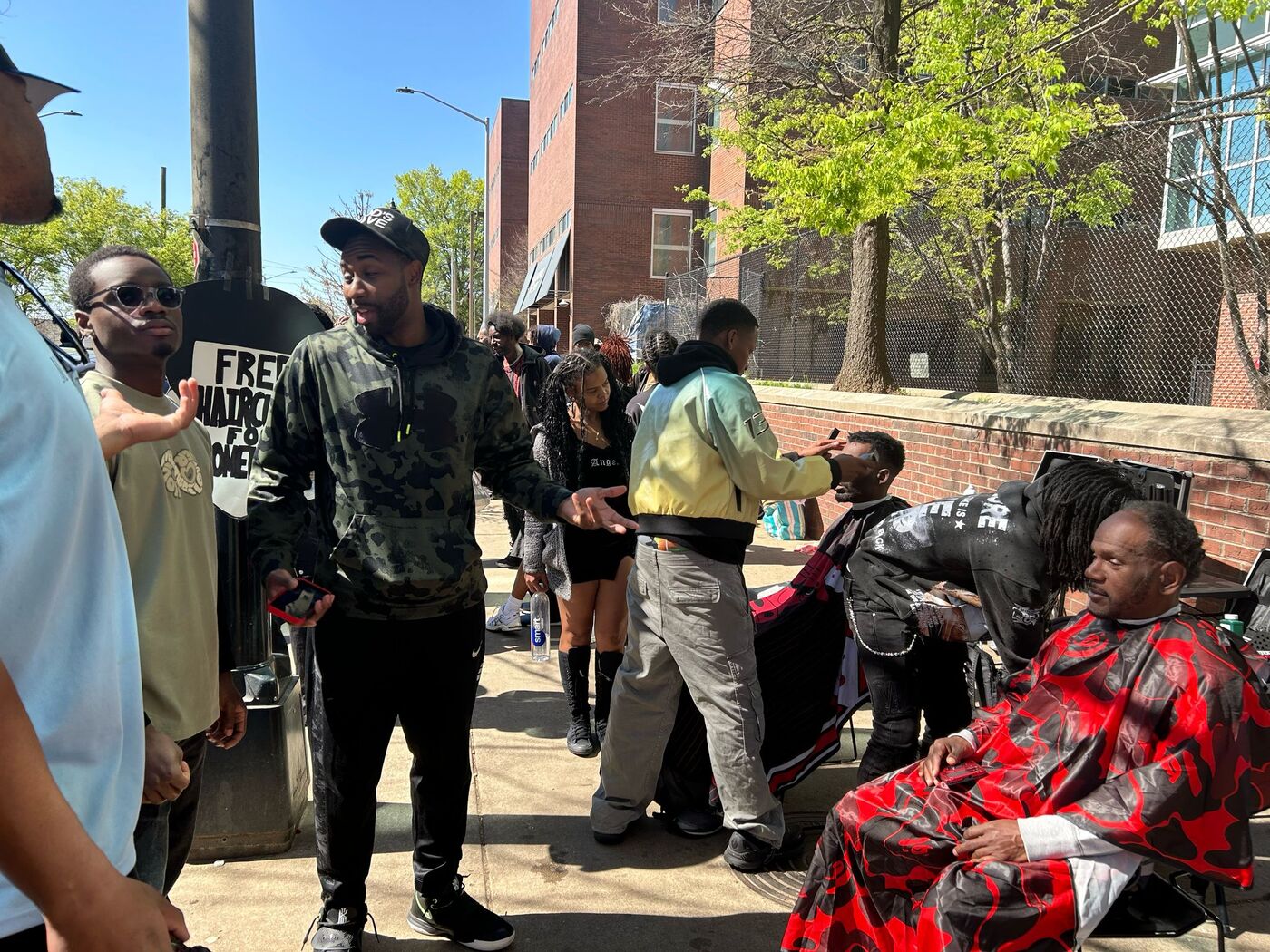 Wide view of a street outreach event with an active haircut in the foreground