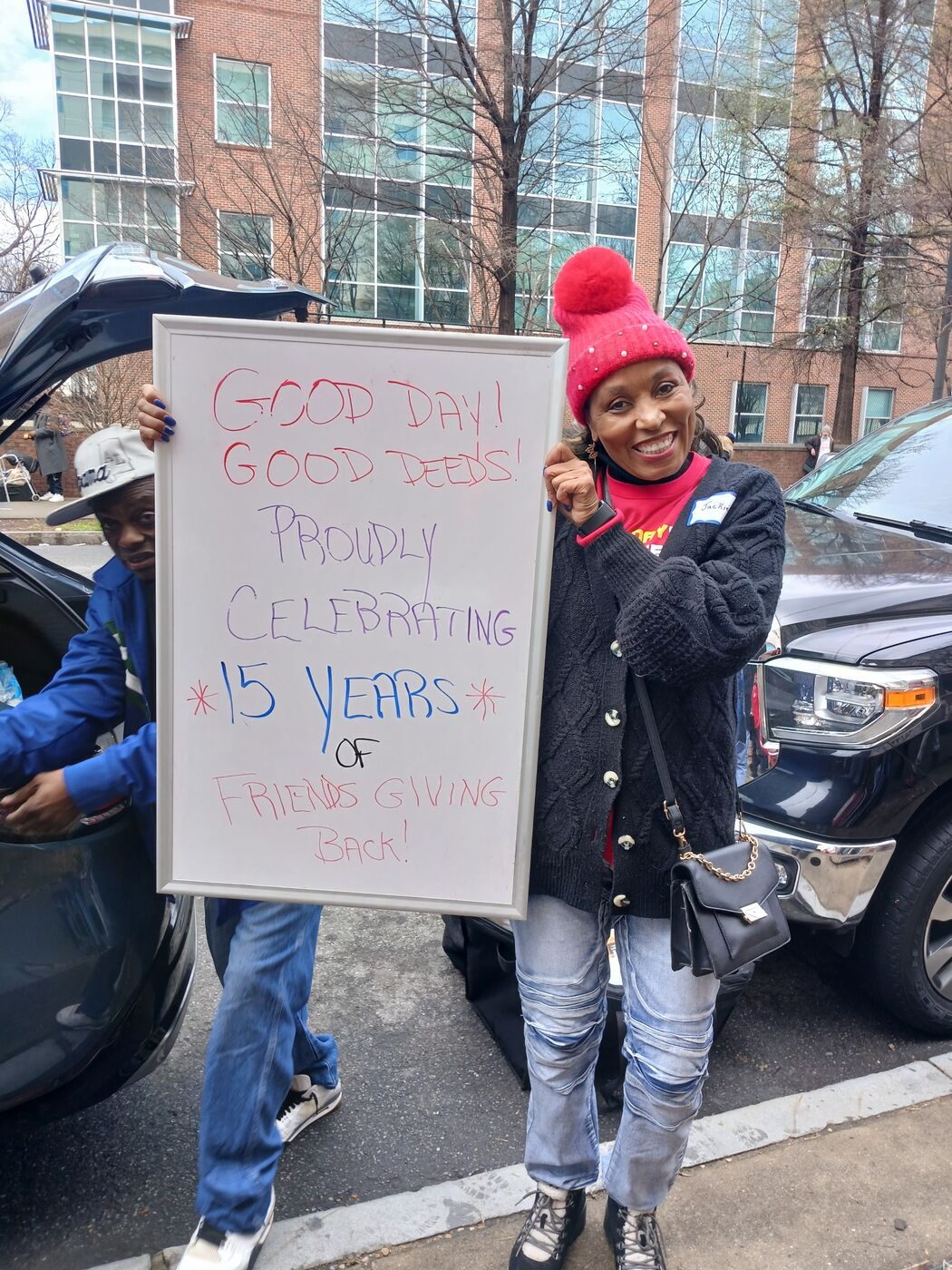 Volunteer holding a 15 years of Friends Giving Back milestone sign